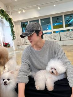 a woman sitting on the floor with two small white poodles in her lap