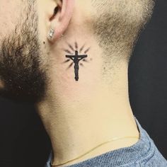 a man's neck with a cross tattoo on his left side behind the ear