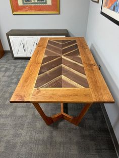 a wooden table sitting on top of a carpeted floor next to two framed pictures