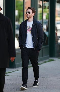 a man walking down the street with sunglasses on his head and one hand in his pocket