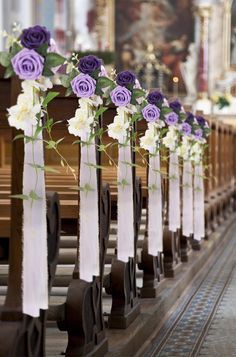 purple and white flowers are tied to the pews