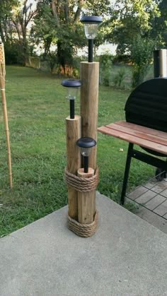 an outdoor fire pit made out of wood and rope with two lights on each pole