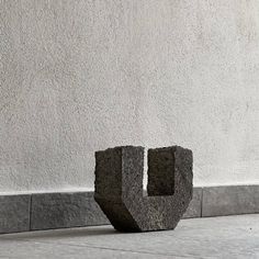 a stone sculpture sitting in front of a white wall