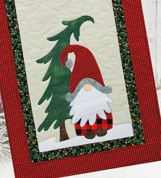 a quilted christmas card with a santa clause holding a pine tree on it's back