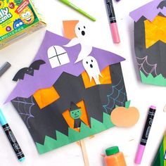 halloween crafts and supplies laid out on a white table with markers, crayons, pencils