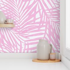 a pink palm leaf wallpaper in a kitchen with white counter tops and wooden shelves