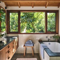 a bath room with a large window and a bench in front of the tub area