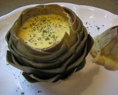 an artichoke is sitting on a white plate