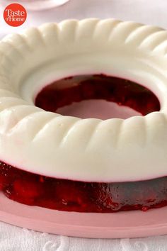 a cake with white frosting and red jelly on it sitting on a pink plate