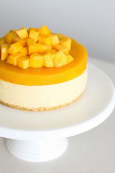 a cheesecake topped with mango slices on a white cake plate