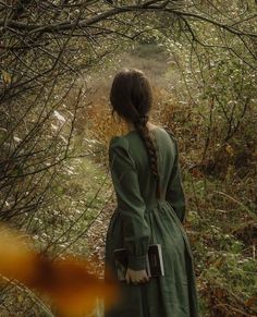 a woman is standing in the woods with her back to the camera and looking at something