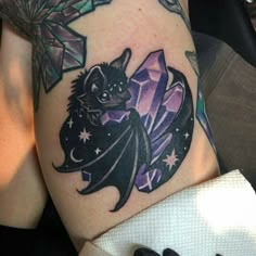 a bat tattoo on the leg of a woman's thigh with stars around it