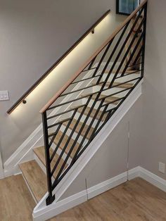 a stair case with wooden handrails and metal railing on the bottom floor in a home