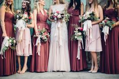 a group of women standing next to each other wearing dresses and holding bouquets in their hands