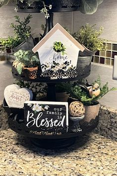 a three tiered tray with potted plants on it and a sign that reads, our family is blessing