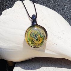 Amazing galaxy statement glass pendant necklace. At the heart of this extraordinary handmade borosilicate glass pendant lies the pure silver and pure gold fuming technique, which brings a touch of magic to the glass. Watch in awe as the silver and gold particles create a mesmerizing display of colors, gracefully transitioning from yellows to an array of captivating shades of orange and green. The dark-colored glass background serves as a cosmic canvas, enhancing the celestial effects and adding Adjustable Glass Round Pendant Necklace, Minimalist Glass Jewelry For Gifts, Minimalist Glass Jewelry Perfect For Gifts, Handmade Minimalist Clear Necklace, Artistic Glass Round Pendant Necklaces, Artistic Glass Round Pendant Necklace, Artistic Glass Necklace With Round Pendant, Murano Glass Pendant Necklace For Gift, Nickel-free Recycled Glass Necklace As A Gift