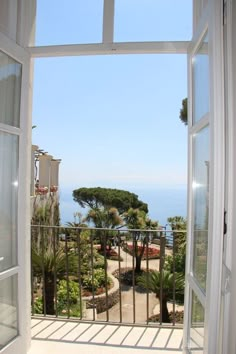 an open window looking out at the ocean and trees in front of it on a sunny day