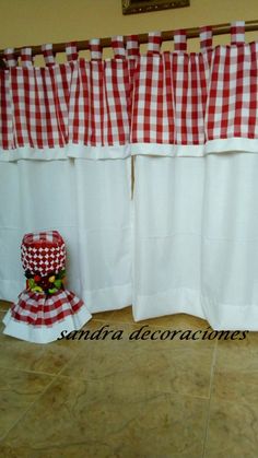 a red and white checkered kitchen curtain next to a potted plant on the floor