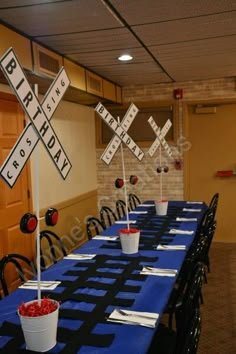 a blue table cloth topped with cups filled with red flowers and paper crosses on top of it