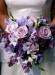 a bride holding a bouquet of purple flowers