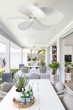 an outdoor living area with white furniture and plants on the table, in front of sliding glass doors