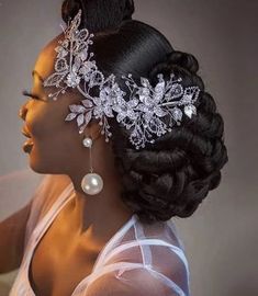 a woman wearing a bridal headpiece with pearls and flowers on it's side