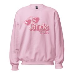 "Get ready to rock the pink vibes with our Barbie-themed \"Bride-to-Be\" custom sweatshirts! 💖👰 Designed for your coziest moments, these sweatshirts are like a soft, snug embrace for your skin. Crafted from a dreamy blend of 50% preshrunk fabric, they're tailor-made for your pre-wedding escapades. And the excitement doesn't stop there - sizes ranging from S to 5XL mean you can flaunt an oversized, relaxed look by sizing up! But here's the cherry on top: these sweatshirts are a canvas for customization. Add the bride's name and the year to make them as unique as her one-of-a-kind love story. Whether you're painting the town red or lounging with your squad 🥂, our Barbie magic sweatshirts will have you owning the bride-to-be scene. Get ready to say \"I do\" to style, comfort, and a sprinkl Pink Crew Sweatshirt With Graphic Print, Pink Crew Neck Sweatshirt With Graphic Print, Customizable Trendy Pink Tops, Pink Relaxed Fit Fleece Sweatshirt, Pink Fleece Tops With Graphic Print, Pink Fleece Sweatshirt With Letter Print, Pink Cotton Sweatshirt With Custom Print, Customizable Long Sleeve Pink Sweatshirt, Customizable Pink Long Sleeve T-shirt