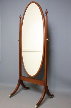 an oval wooden mirror on stand against a wall