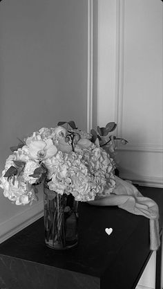 a vase filled with flowers sitting on top of a black table next to a mirror