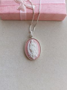 A handmade sterling silver pendant holding a resin pink and white cameo featuring Our Lady of Guadalupe. The back is all covered in solid silver. Measurement of pendant excluding bail is 3.00 cm x 2.00 cm Please note the items are shiner than shown in photos.and colour may vary a bit in photo.  All items will be sent by registered airmail in a jewelry gift box and an organza bag. You can view more of my work in this Etsy shop or Facebook page TrulyFiligree. Resin Light, Our Lady Of Guadalupe, Lady Of Guadalupe, Cameo Necklace, Handmade Sterling Silver, Our Lady, Organza Bags, Jewelry Gift Box, Malta