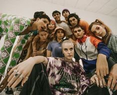 a group of young people posing for a photo in front of a white wall with one person's hand on the ground