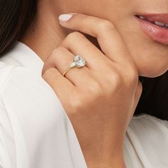 a woman wearing a gold ring with an oval shaped diamond on the center and side