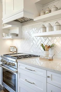 a kitchen with white cupboards and an oven in the center, surrounded by open shelving