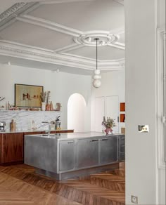 a kitchen with an island in the middle and marble counter tops on both sides, surrounded by wood flooring