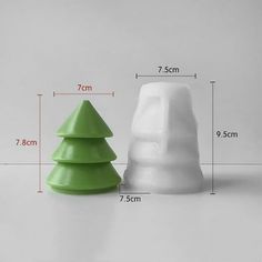 two white and green ceramic christmas trees on a table next to each other, with measurements