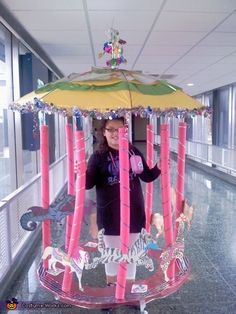 a woman standing under an umbrella shaped like a carousel