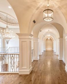 an empty hallway with chandeliers and wooden floors