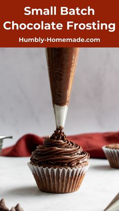 a chocolate frosted cupcake being piped into it with a small batch of chocolate frosting on top