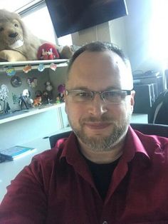 a man sitting at a desk with stuffed animals in the background