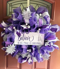 a purple and white christmas wreath on the front door