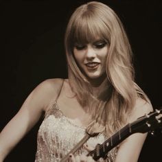 a woman with long blonde hair holding a guitar