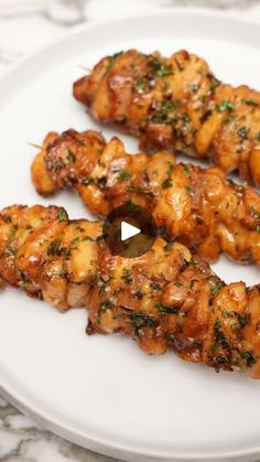 chicken skewers on a white plate with parsley sprinkled around them