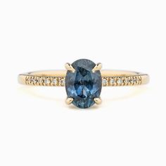 an oval blue sapphire and diamond ring in yellow gold with diamonds around the band, on a white background