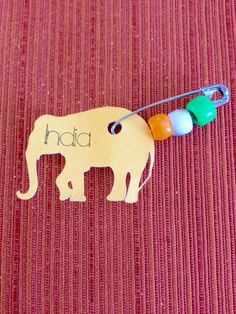 an elephant name tag attached to a string with beads on it's back and the word had written in small letters