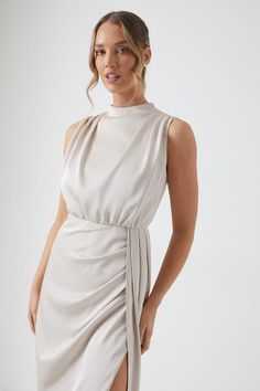 a woman is wearing a white dress with a slit down the side and she has her hands on her hips