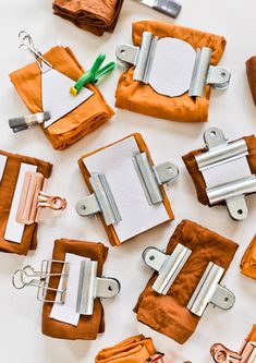 several pieces of orange fabric with metal clips and paper clips attached to each other on a white surface