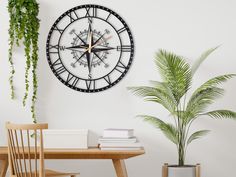 a clock on the wall next to a table with a potted plant in it