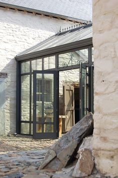 an open door to a white brick building with glass walls and doors on both sides