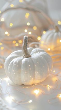 a white pumpkin sitting on top of a table next to some string lights in the background