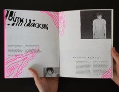 a person holding an open book in their left hand, with pink and black graphics on it